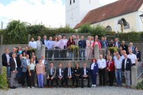 Die rund 70 Gäste des ILE Netzwerktreffens posieren am Dorfplatz, auf einer Treppe vor der Kirche in Haunersdorf, für ein Gruppenfoto